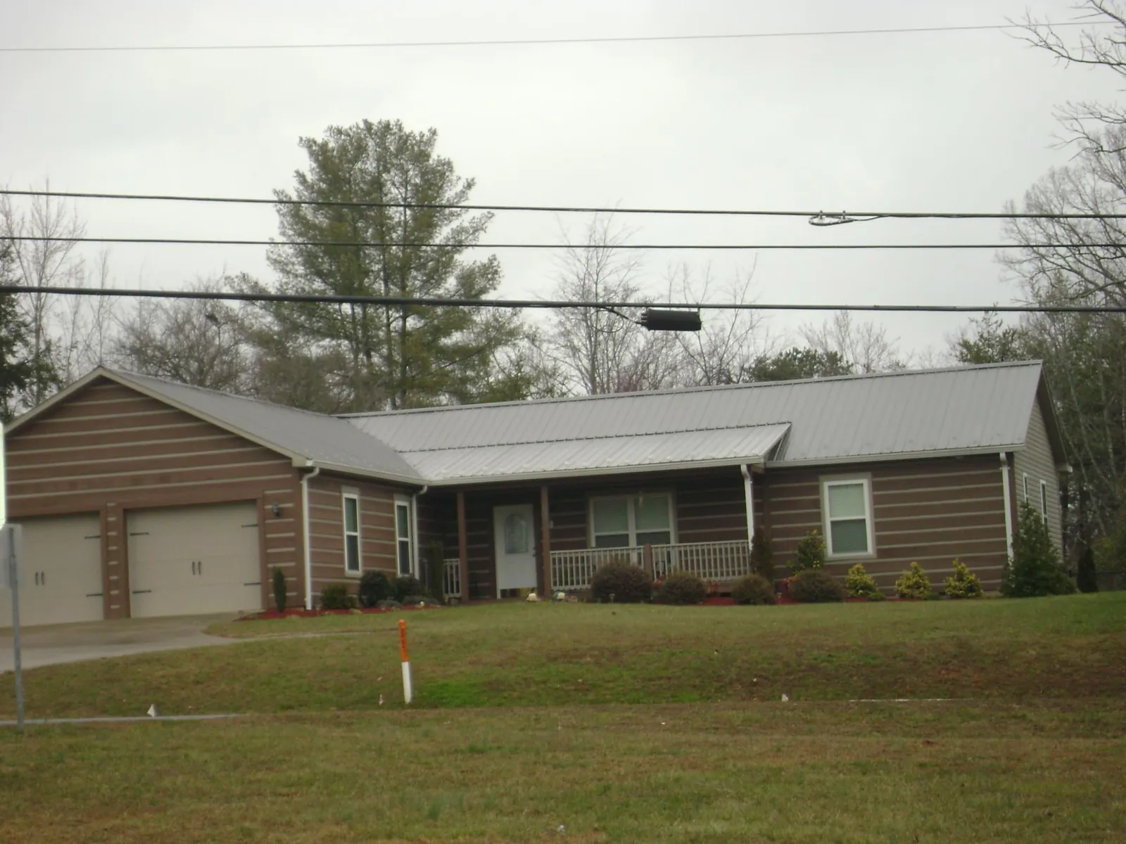 Gray metal roof on a log sided ranch home with a front porch in Albany