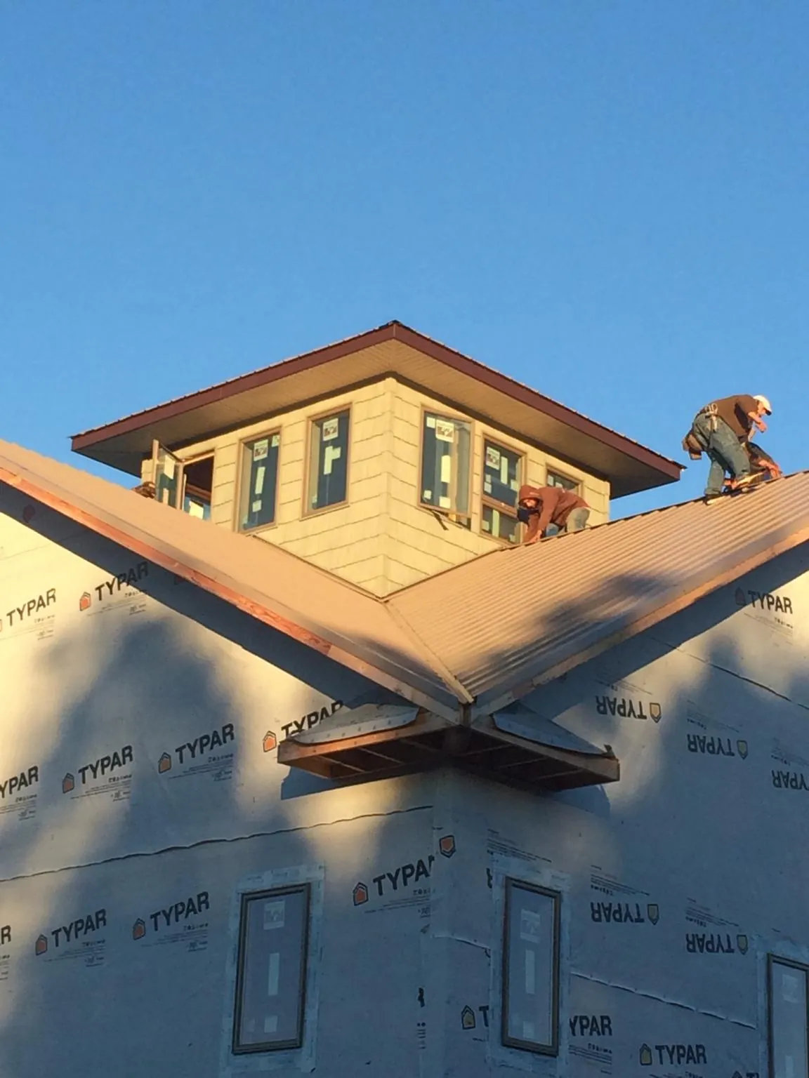 Roofers working around a rooftop cupola on a new metal roof at sunset — Roof Waterproofing in Albany by Roofing Brothers